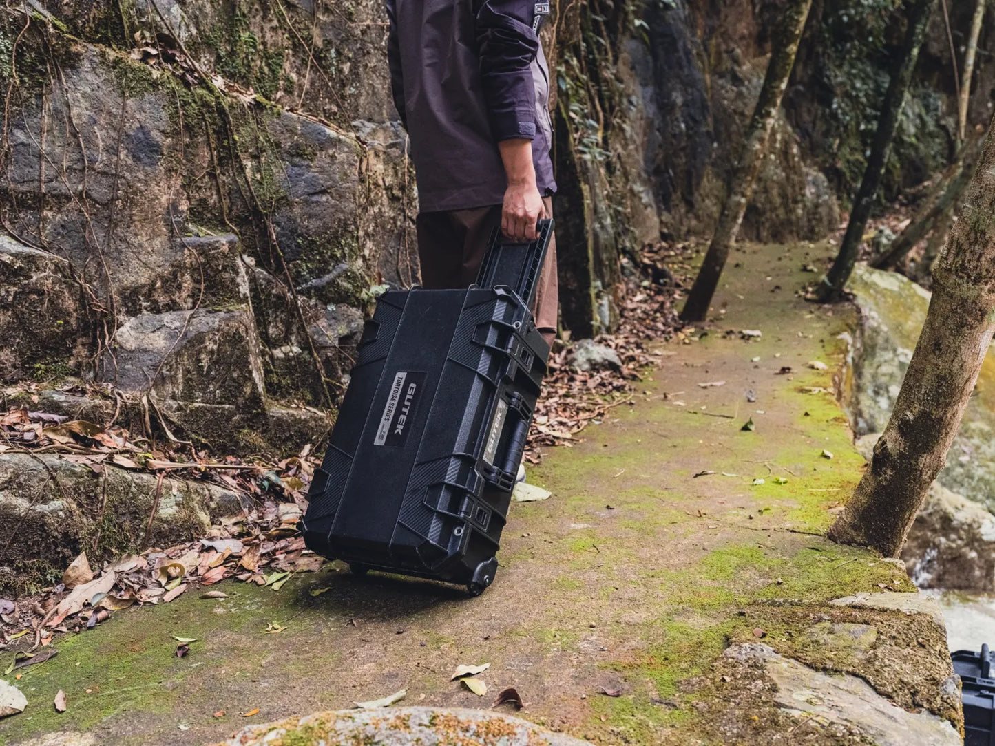 Gutek T-300 hard case being rolled over rough terrain showing durability and mobility