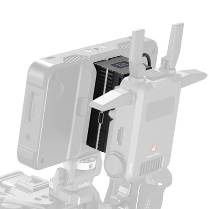 Close-up of the SmallRig dummy battery adapter mounted between a wireless video receiver and monitor.