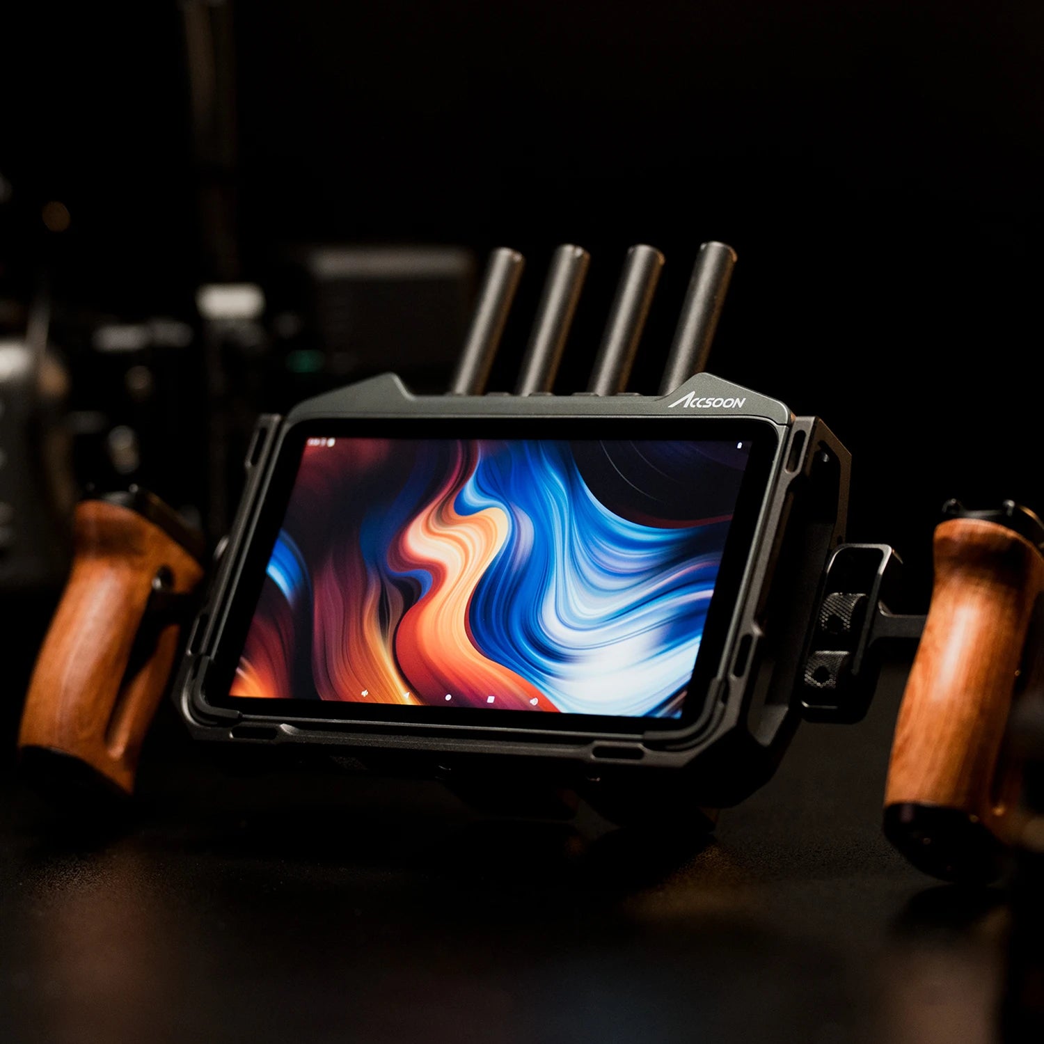Accsoon CineView M7 Pro wireless monitor with quad antennas placed on table between wooden camera rig handles for professional on set monitoring