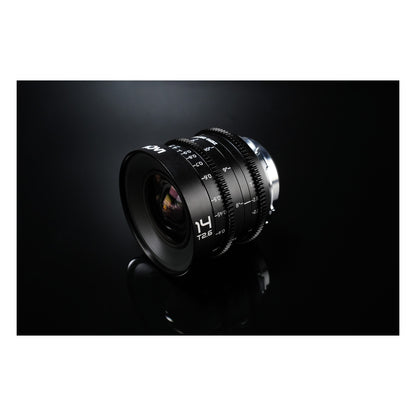 Laowa 14mm T2.6 photographed against dark grey/black background with dramatic sidelighting, showing texture and dimensionality of barrel.