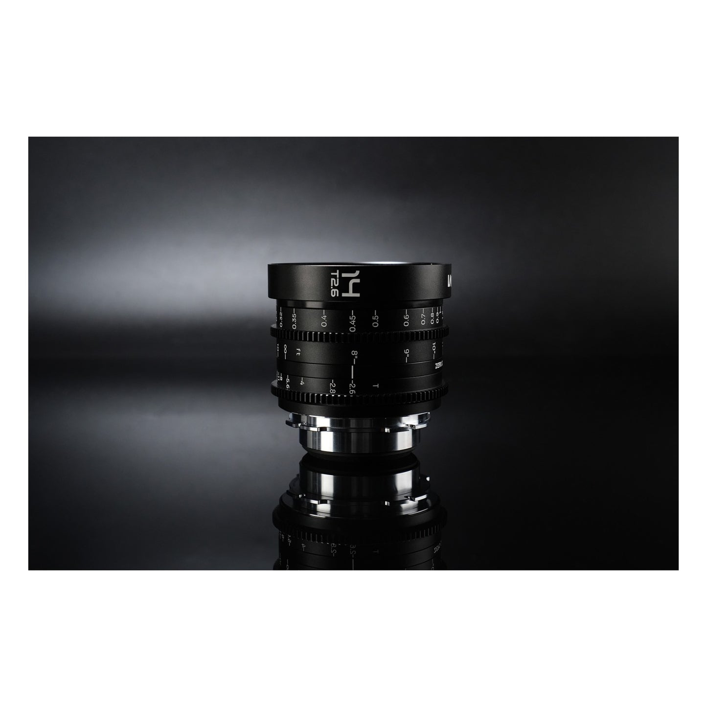 Laowa 14mm T2.6 lens standing upright on reflective surface against dark studio backdrop, showing mirrored base image.