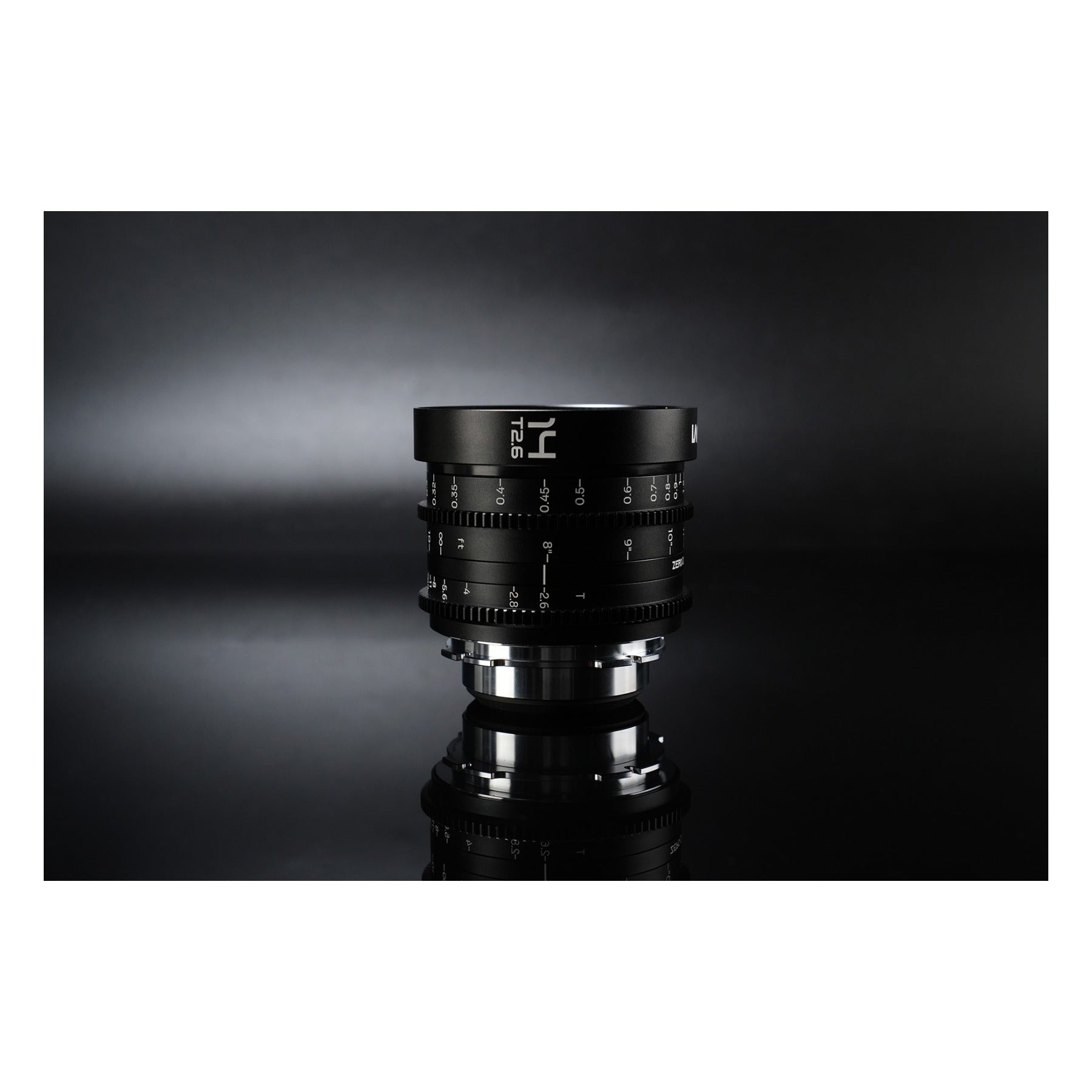 Laowa 14mm T2.6 lens standing upright on reflective surface against dark studio backdrop, showing mirrored base image.