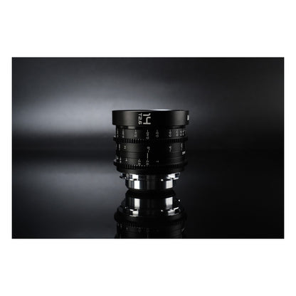 Laowa 14mm T2.6 lens standing upright on reflective surface against dark studio backdrop, showing mirrored base image.