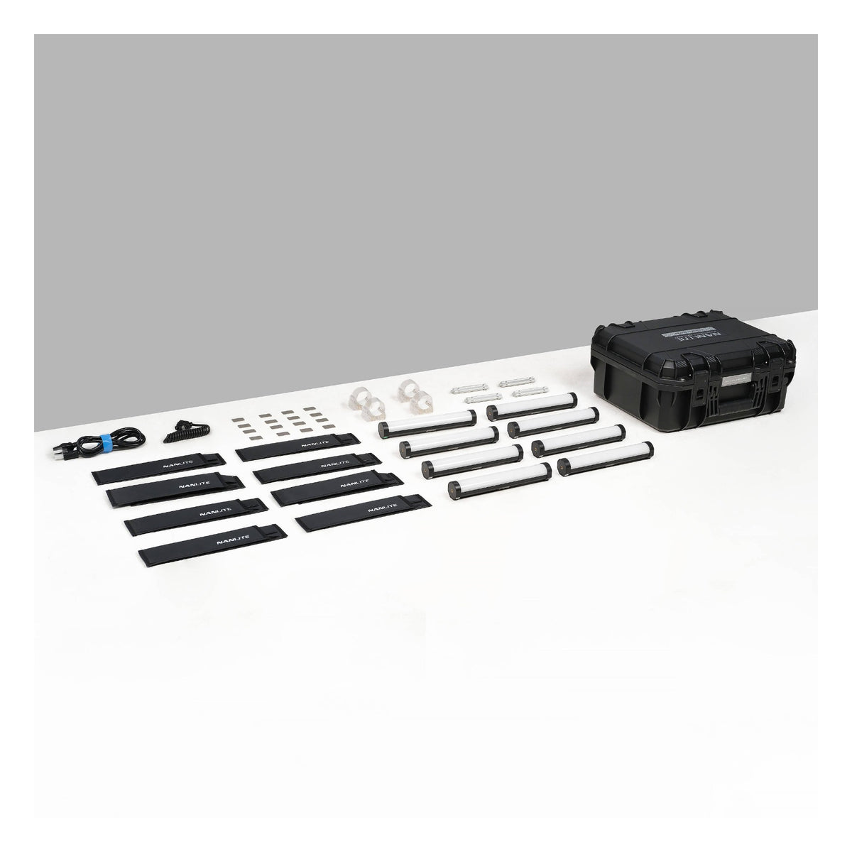 All 8-light kit components arranged on white surface: tubes, batteries, clamps, sync cables, mounting brackets, power adapter, and closed case at right.