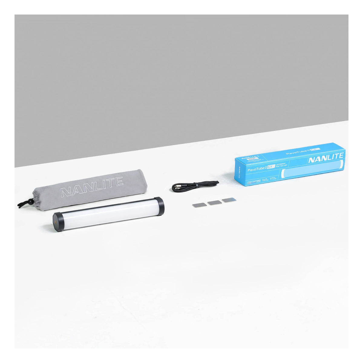Angled three-quarter view of blue PavoTube II 6XR retail box, gray carrying case, white tube, cable, and filter set arranged on white and gray surfaces.