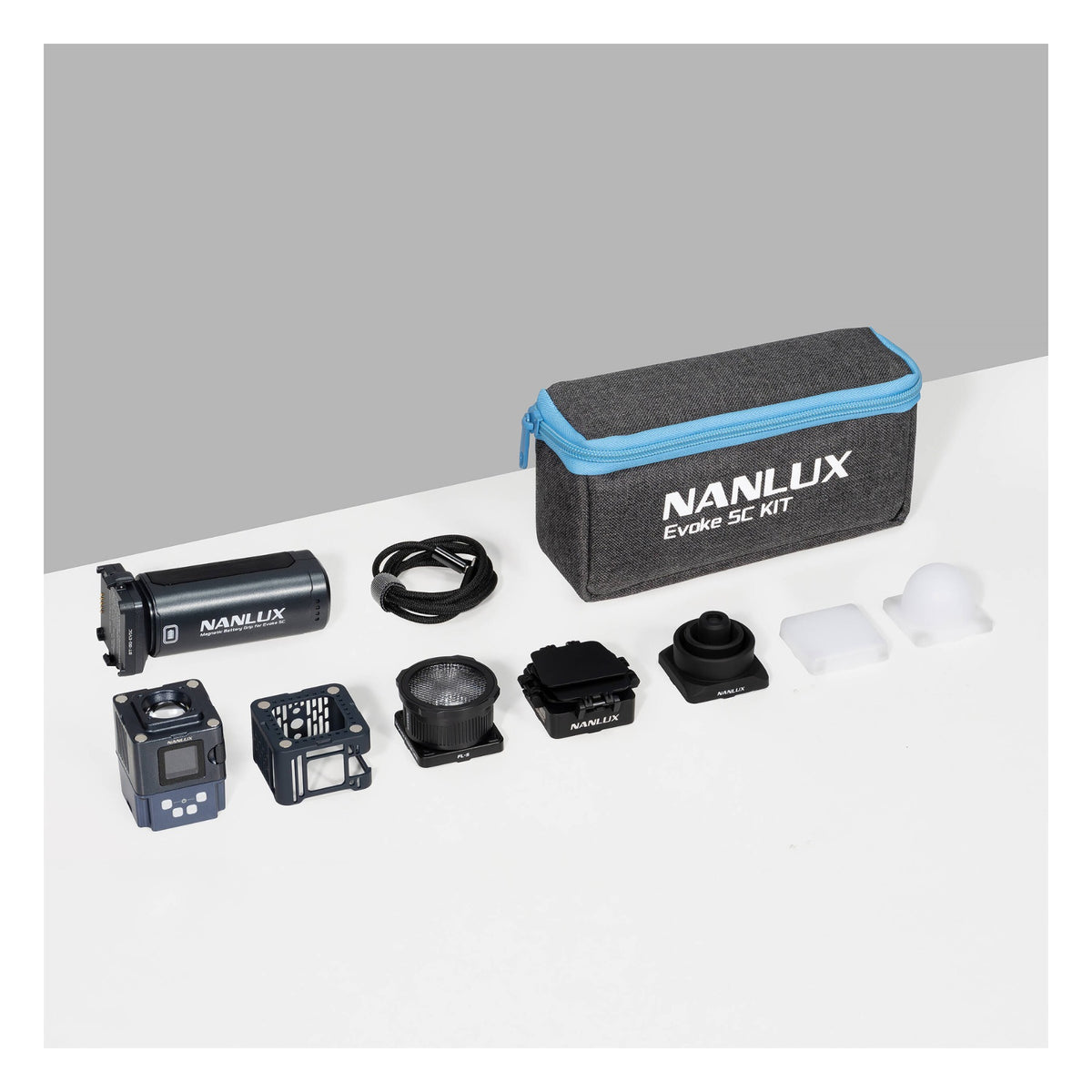 Evoke 5C kit components displayed at an angled three-quarter perspective on split white and grey surface: carrying case elevated, spotlight tube, controller, lens assembly, and light-shaping accessories arranged below.